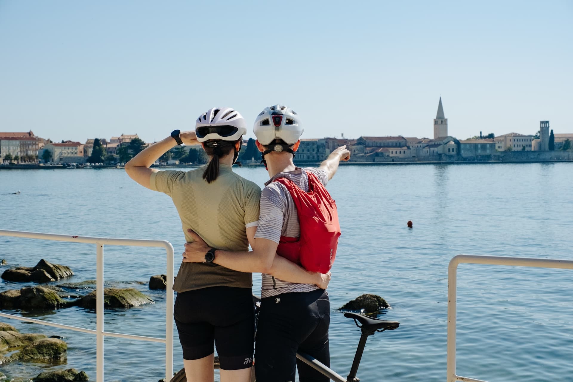 Cyclists viewing historic town across Adriatic coast with bell tower