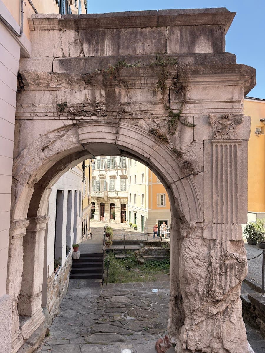 Ancient stone archway framing a historic city square with buildings