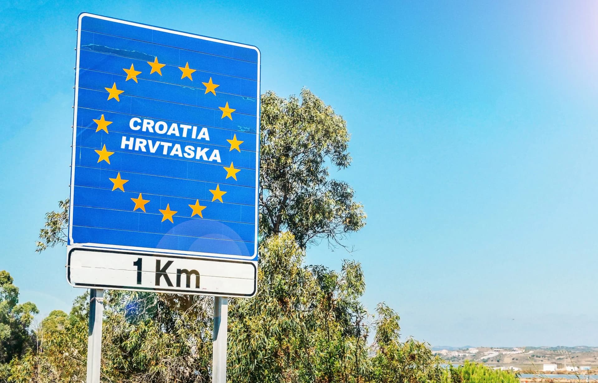 Road sign on the border of a European Union country, Croatia 1km ahead with blue sky copy space