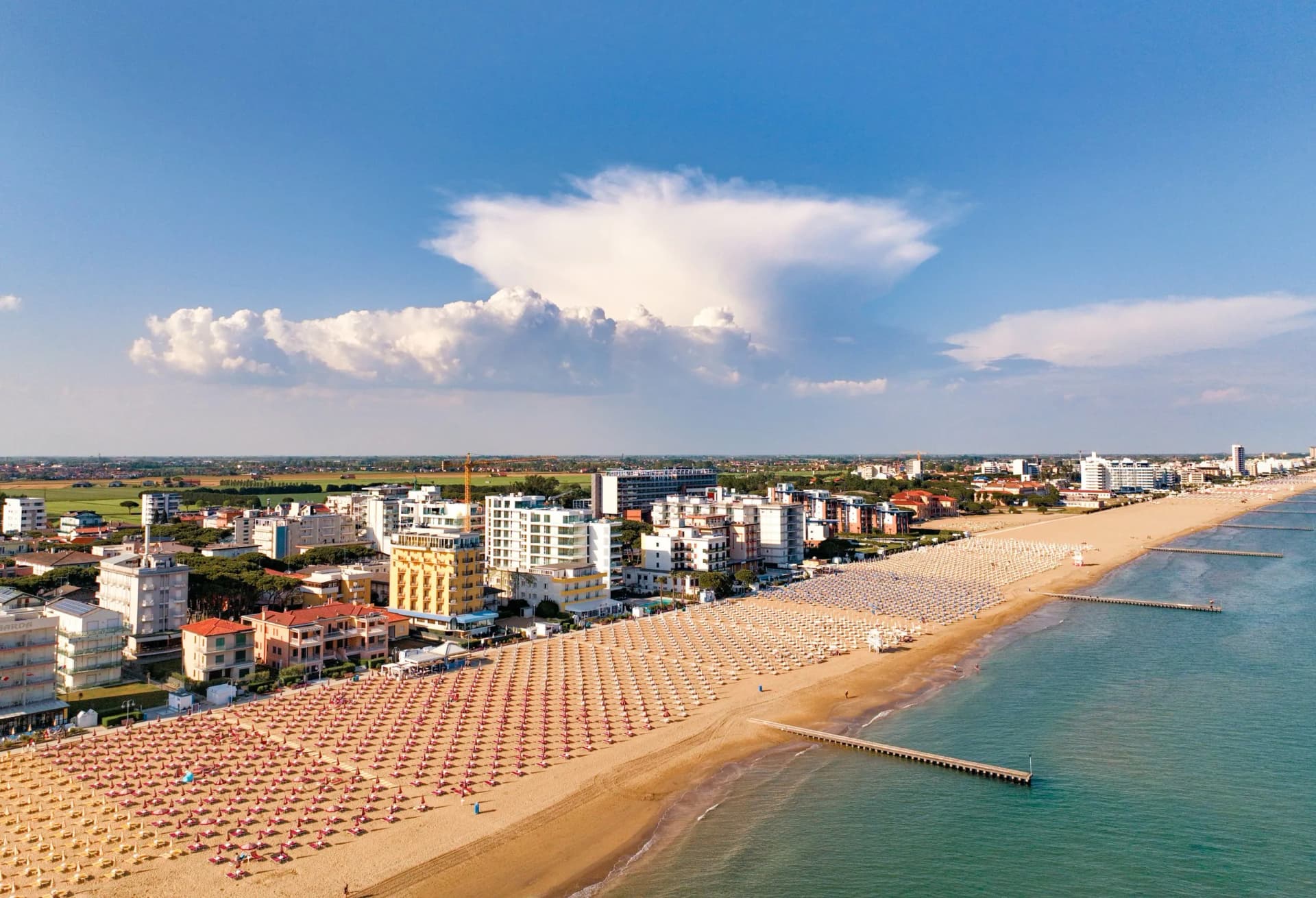 Jesolo - spiaggia con lettini e ombrelloni in località estiva vista dall'alto con vista sulla città