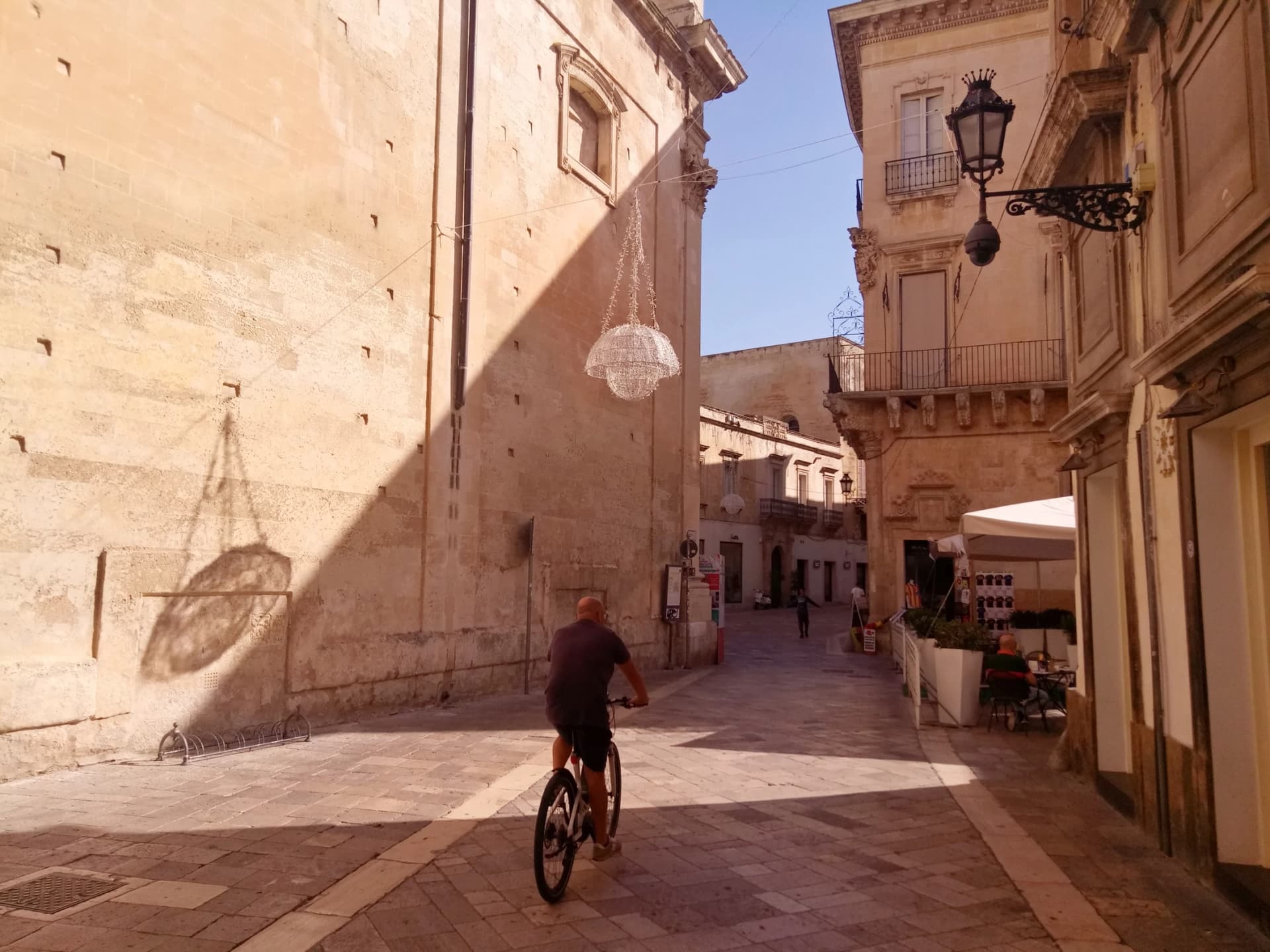 Lecci, Italy. Sunrise in old town. Play of light and shadow. Sityscape with bicycling man.