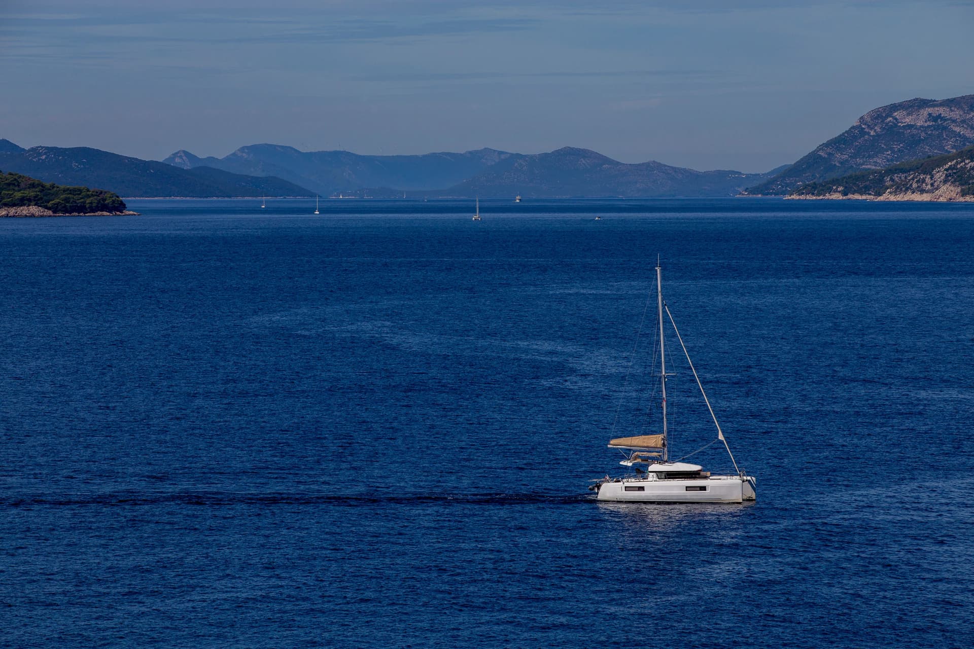 yacht cruises on the Adriatic Sea in the region of Dubrovnik, Croatia, with islands in the background, sunny day, clear weather, intense blue.