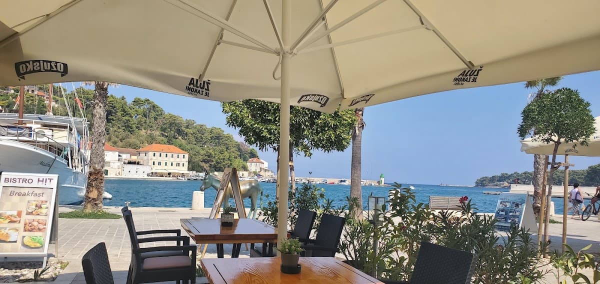 Outdoor cafe seating overlooking harbor with docked boat and sea view