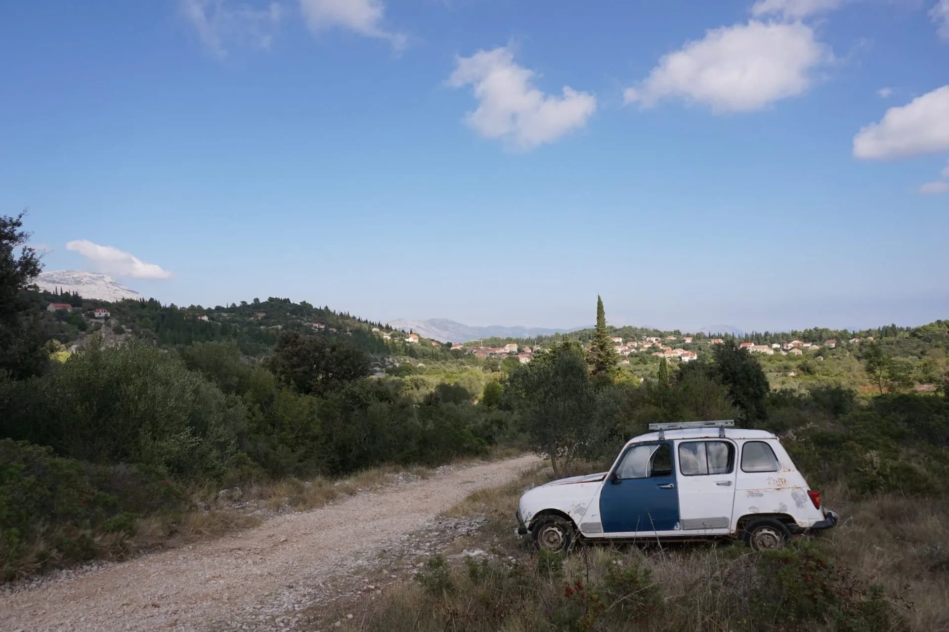 Old white and blue Renault 4 parked on a dirt track overlooking Korcula Island hinterland.